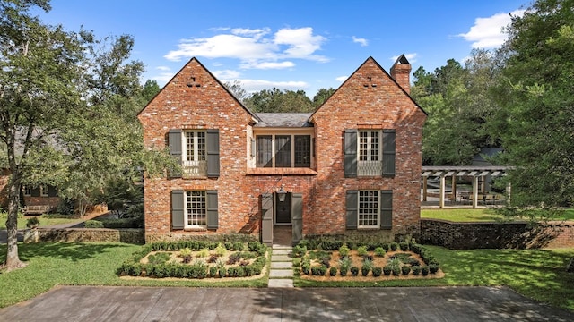 tudor home with a front yard and a pergola