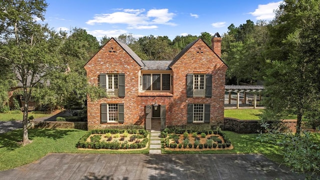 tudor house with a pergola and a front yard