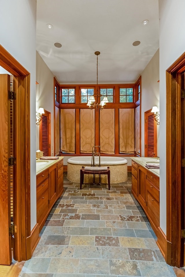 bathroom featuring a bathing tub, vanity, and a chandelier