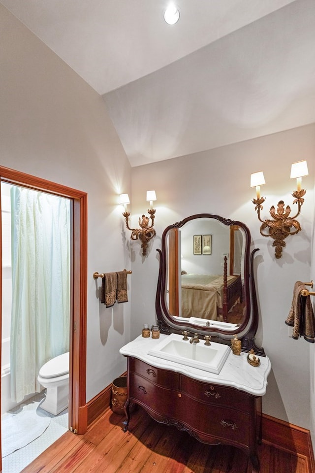 bathroom with vanity, wood-type flooring, lofted ceiling, and toilet