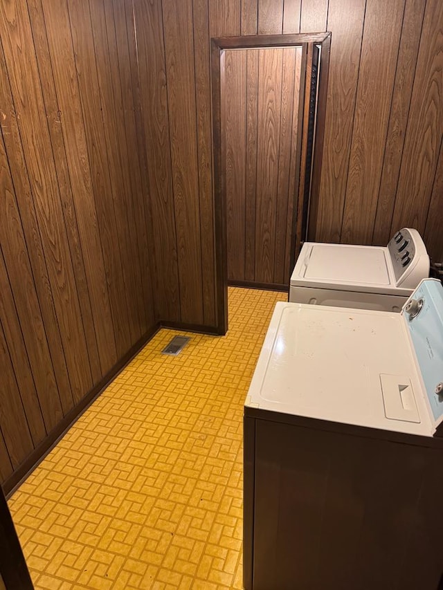 laundry room featuring washer and dryer and wood walls