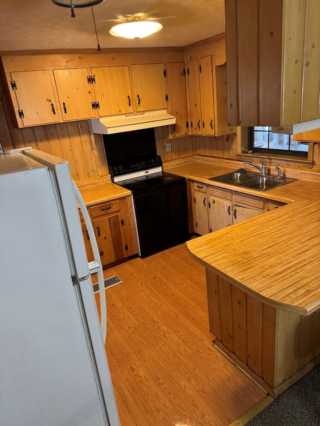 kitchen with white appliances, sink, range hood, light hardwood / wood-style floors, and kitchen peninsula