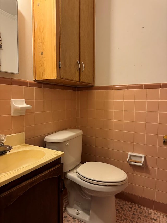 bathroom featuring tile patterned flooring, vanity, toilet, and tile walls