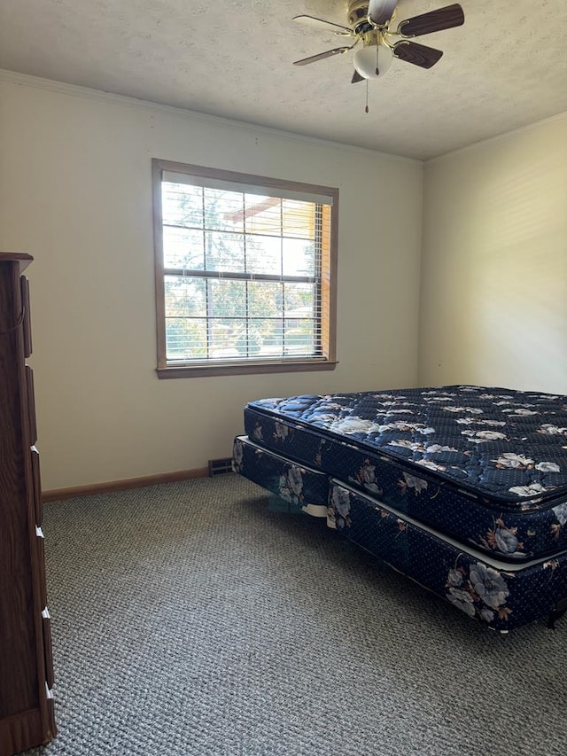 carpeted bedroom with ceiling fan and a textured ceiling