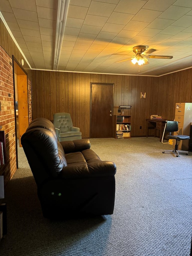 carpeted living room with wood walls, crown molding, and ceiling fan