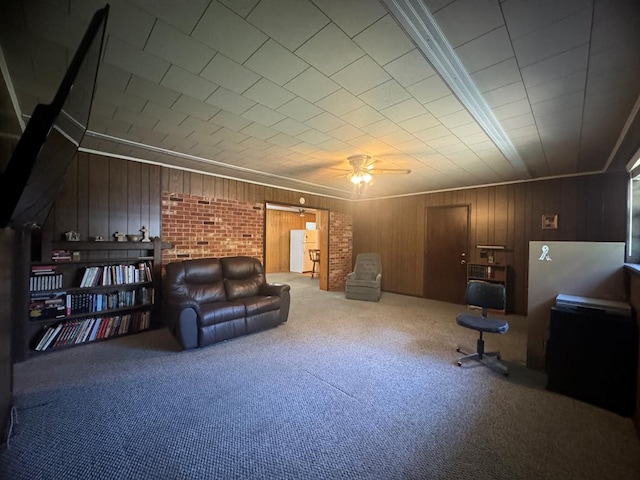 living area with carpet, ceiling fan, and wood walls