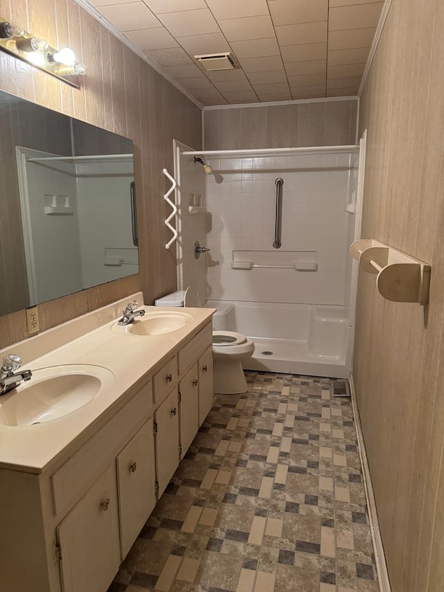 bathroom featuring wooden walls, crown molding, vanity, and toilet