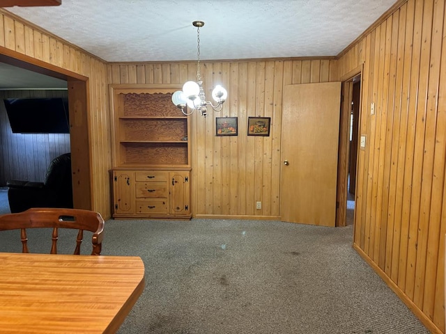 unfurnished dining area with a chandelier, a textured ceiling, carpet floors, and wooden walls