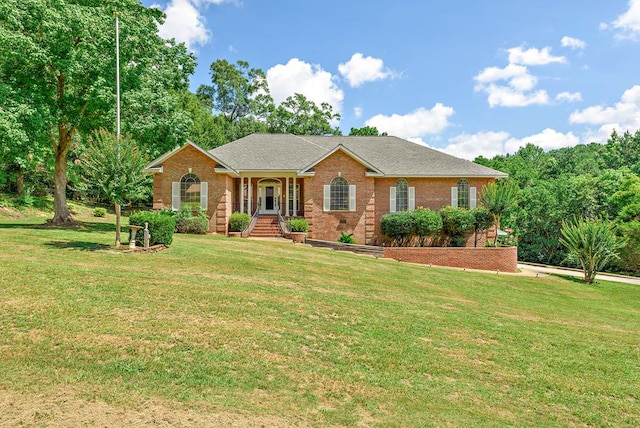 ranch-style home featuring a shingled roof, a front yard, and brick siding