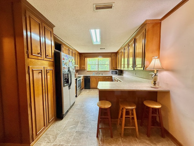 152 W Cox St, Slocomb, AL 36375 - kitchen with appliances with stainless steel finishes, brown cabinetry, light countertops, a peninsula, and a textured ceiling