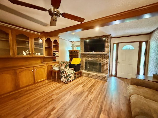 152 W Cox St, Slocomb, AL 36375 - living room with light wood-style flooring, ornamental molding, a brick fireplace, a ceiling fan, and a textured ceiling