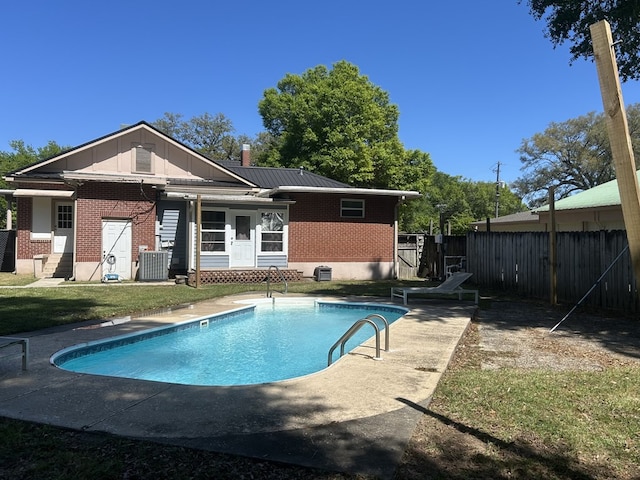 back of house with entry steps, a fenced in pool, fence, and brick siding