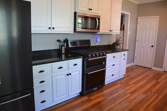 kitchen with white cabinets, appliances with stainless steel finishes, dark wood-style floors, crown molding, and dark stone counters