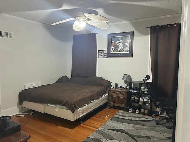 bedroom featuring visible vents, ceiling fan, crown molding, and wood finished floors