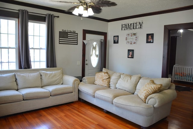 living area with wood finished floors, a textured ceiling, crown molding, and ceiling fan