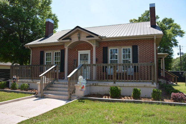 view of front of property featuring brick siding, a porch, and a chimney