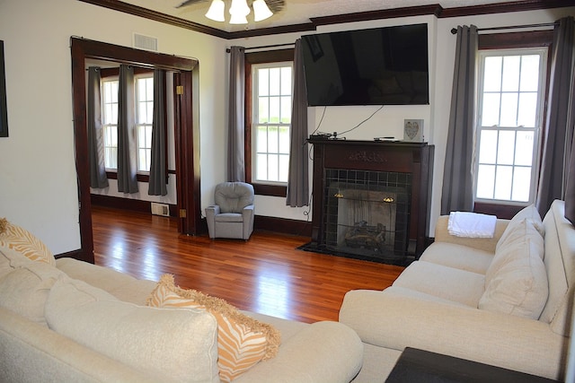 living area with crown molding, visible vents, wood finished floors, and a fireplace