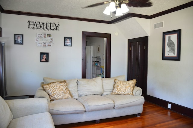living room featuring visible vents, baseboards, ornamental molding, ceiling fan, and wood finished floors