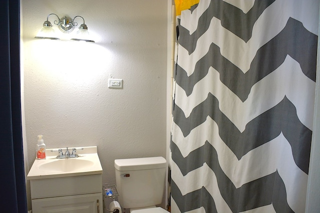 bathroom featuring toilet, curtained shower, and vanity