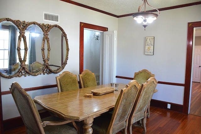 dining room with crown molding, wood finished floors, baseboards, and visible vents