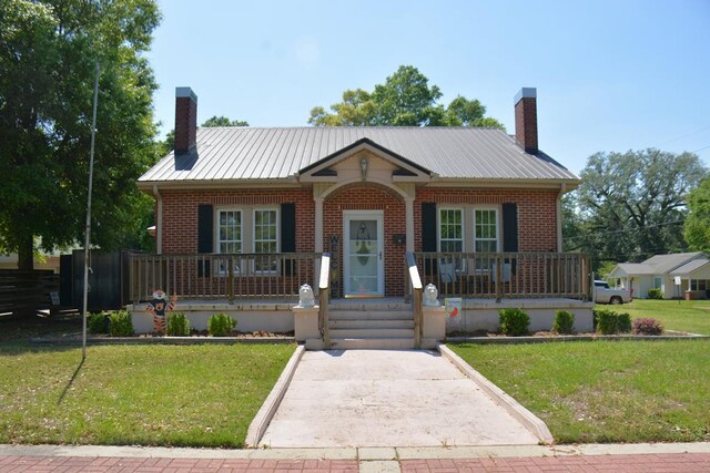 bungalow-style home featuring a front yard, covered porch, and a chimney