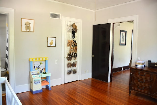 bedroom featuring visible vents, baseboards, crown molding, and wood finished floors