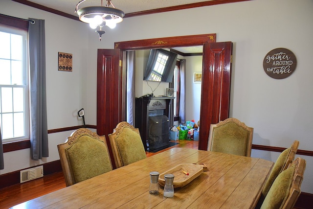 dining area featuring a chandelier, visible vents, crown molding, and wood finished floors