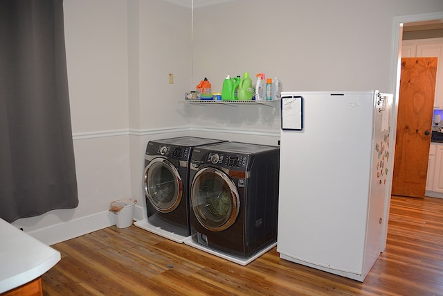 laundry area featuring washer and dryer, laundry area, wood finished floors, and baseboards