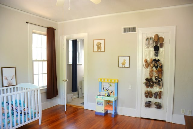 bedroom featuring ornamental molding, visible vents, baseboards, and wood finished floors