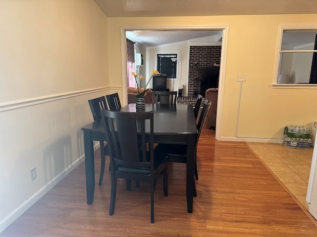 dining space featuring hardwood / wood-style floors and a brick fireplace