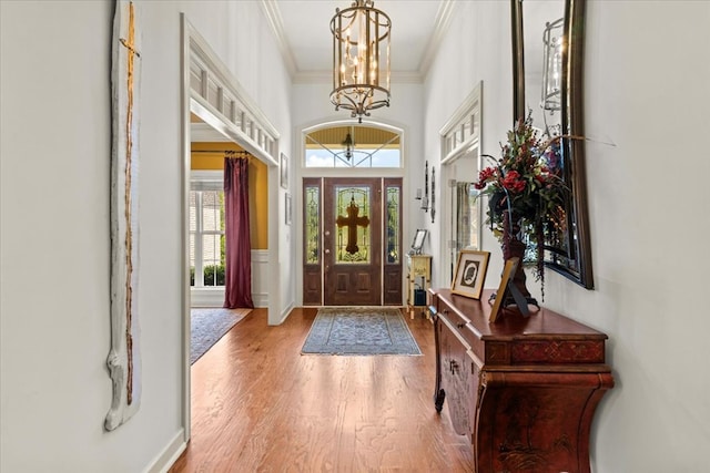 foyer entrance with hardwood / wood-style floors, a notable chandelier, and crown molding