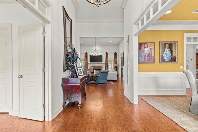 foyer entrance with crown molding, a chandelier, and wood-type flooring