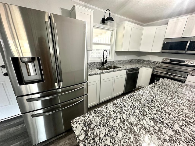 kitchen featuring light stone counters, stainless steel appliances, white cabinetry, and sink