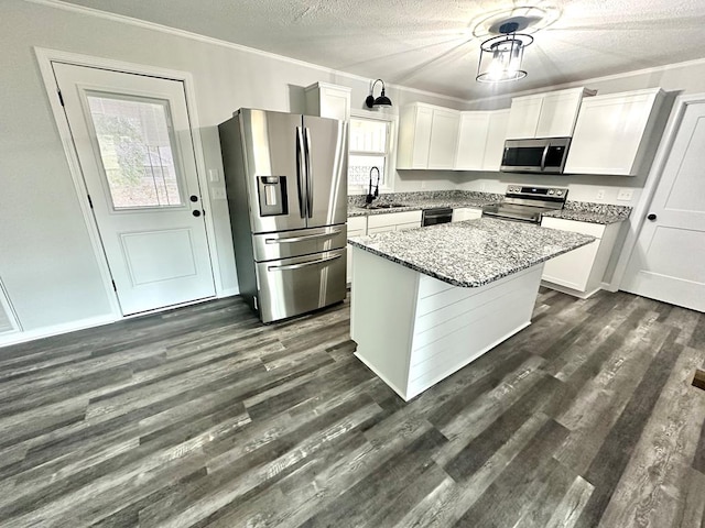 kitchen featuring appliances with stainless steel finishes, light stone counters, sink, white cabinets, and a kitchen island