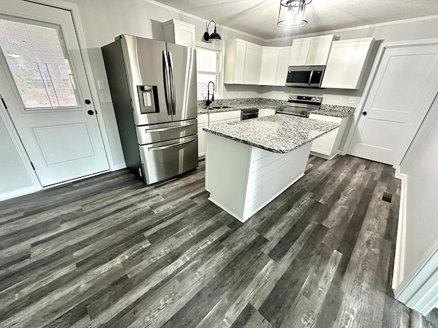 kitchen featuring light stone countertops, stainless steel appliances, dark wood-type flooring, white cabinetry, and a kitchen island