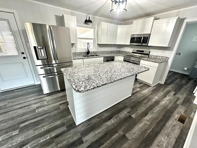 kitchen with a center island, sink, light stone countertops, a textured ceiling, and appliances with stainless steel finishes