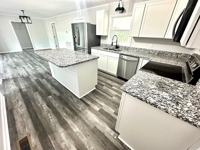 kitchen with a center island, sink, decorative light fixtures, white cabinetry, and stainless steel appliances