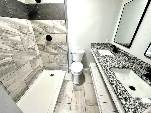 bathroom featuring vanity, toilet, and a tile shower