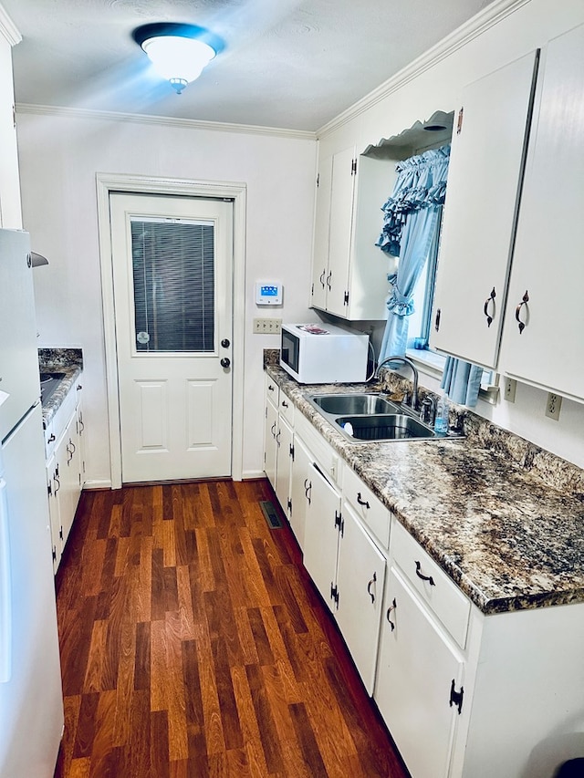 kitchen featuring a sink, dark wood finished floors, white microwave, and white cabinets