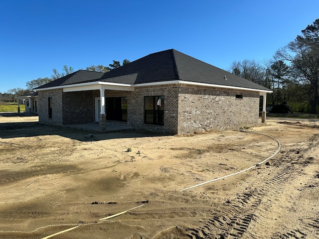 view of side of property featuring brick siding and a patio