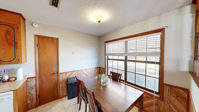 tiled dining space featuring wood walls and a textured ceiling