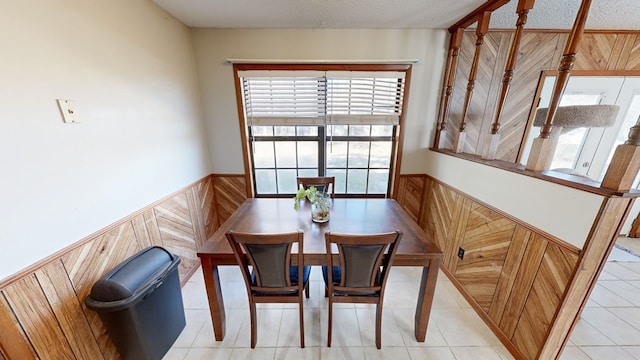 tiled dining space featuring wood walls