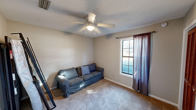 living area with light carpet, a textured ceiling, and ceiling fan