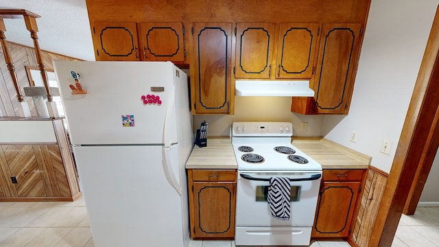 kitchen featuring light tile patterned floors, white appliances, and wooden walls