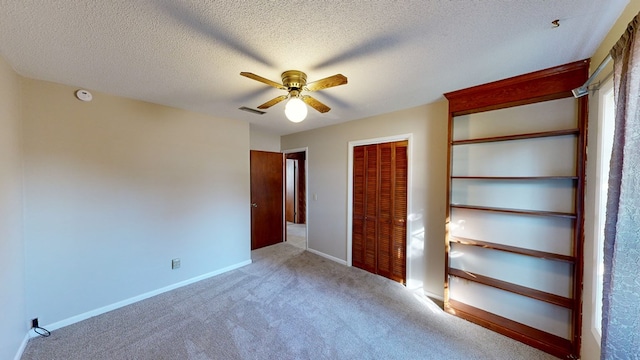 unfurnished bedroom with carpet flooring, a textured ceiling, a closet, and ceiling fan