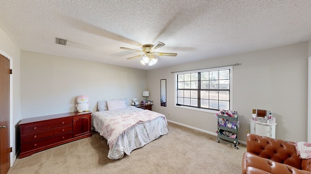 bedroom featuring a textured ceiling, light colored carpet, and ceiling fan