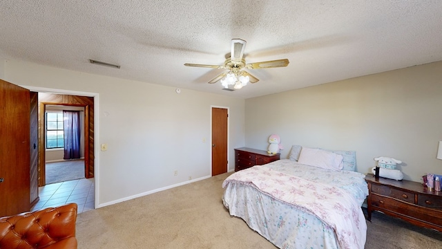 bedroom featuring ceiling fan, light colored carpet, and a textured ceiling