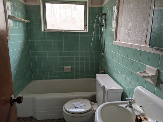 bathroom featuring tiled shower / bath, toilet, and tile walls