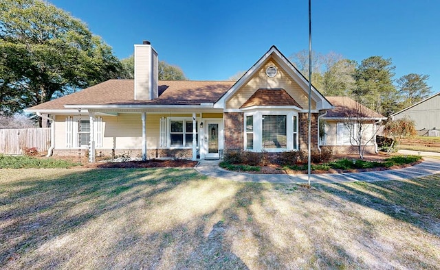 view of front of property with covered porch, fence, a chimney, and a front lawn