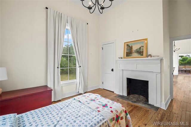 5606 Rocky Creek Rd, Ashford, AL 36312 - bedroom featuring a chandelier, wood finished floors, a towering ceiling, and a fireplace with flush hearth